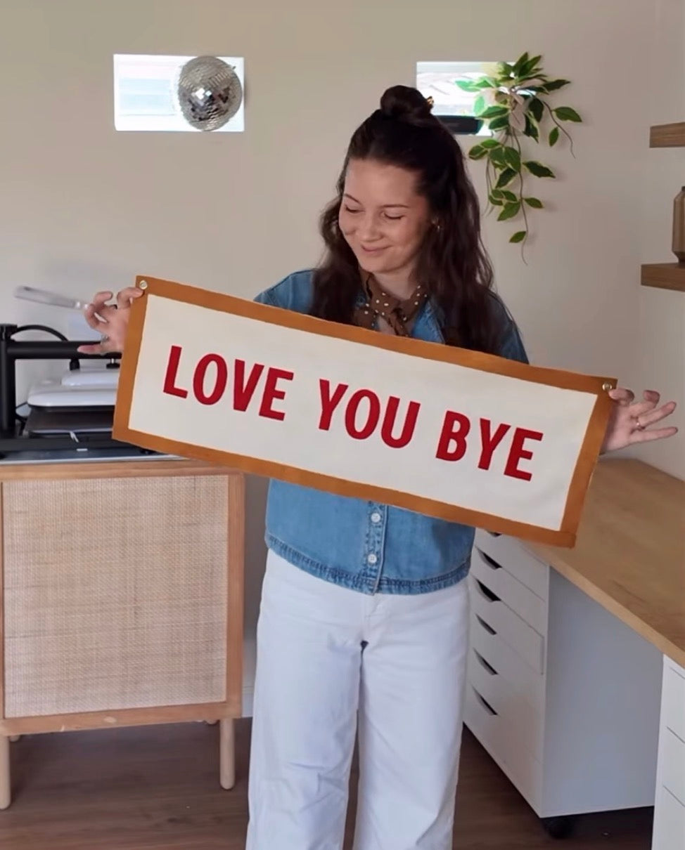 Person holding a sign with 'LOVE YOU BYE' in an office setting